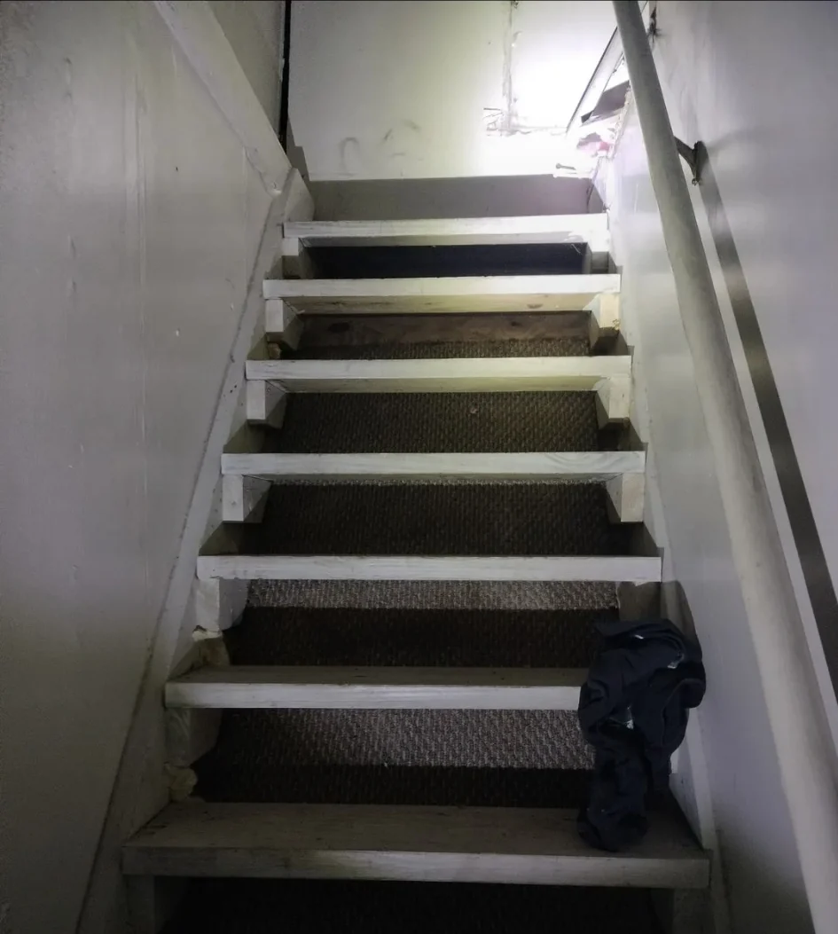 Stairway before final refinishing, showing worn treads and carpet inserts.