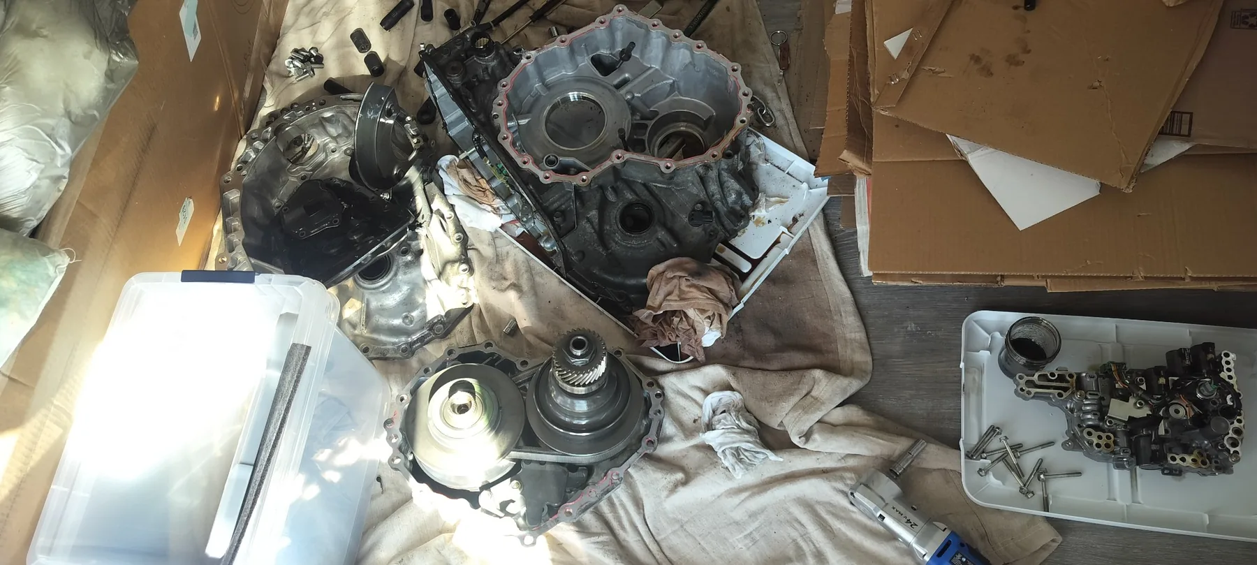 CVT teardown with case sections, pulley and belt assembly, valve body, and fasteners organized for inspection.