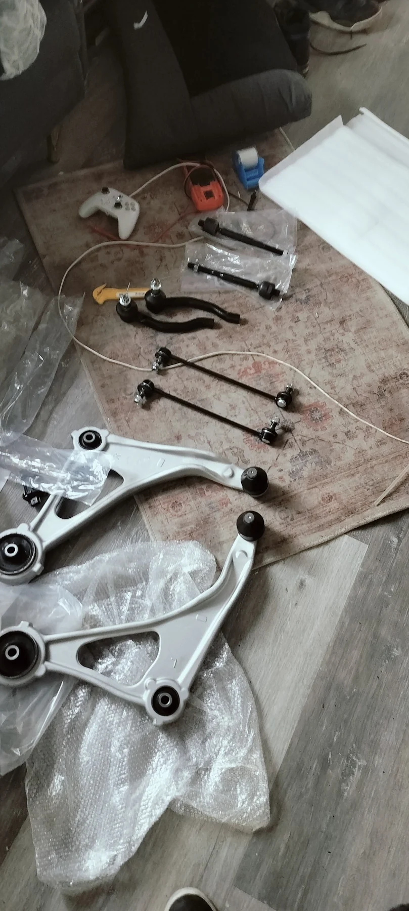 Replacement control arms, links, and steering components organized before installation.
